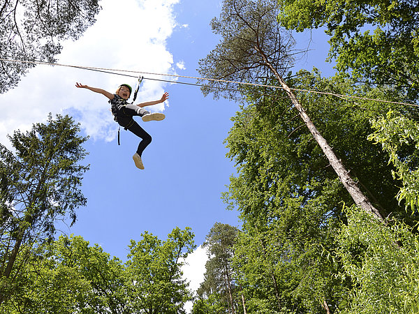 Das Foto zeigt einen unserer Schüler am Flying Fox hoch über den Wäldern und Sauriern des Styrassic Parks in Bad Gleichenberg