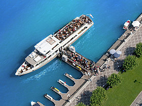 Das Foto zeigt ein Schiff der Wörthersee Schifffahrt beim Landesteg. Von oben fotografiert sieht man gut die Vielzahl an Menschen beim Einstieg